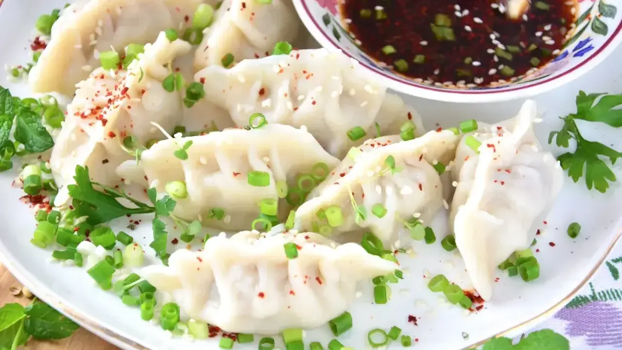 Pyszne pierogi gyoza, posypane szczypiorkiem i sezamem, podane z sosem.