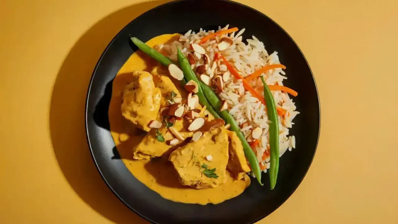 Aksamitny kurczak curry w kremowym sosie, podany z ryżem basmati, fasolką szparagową i płatkami migdałów.