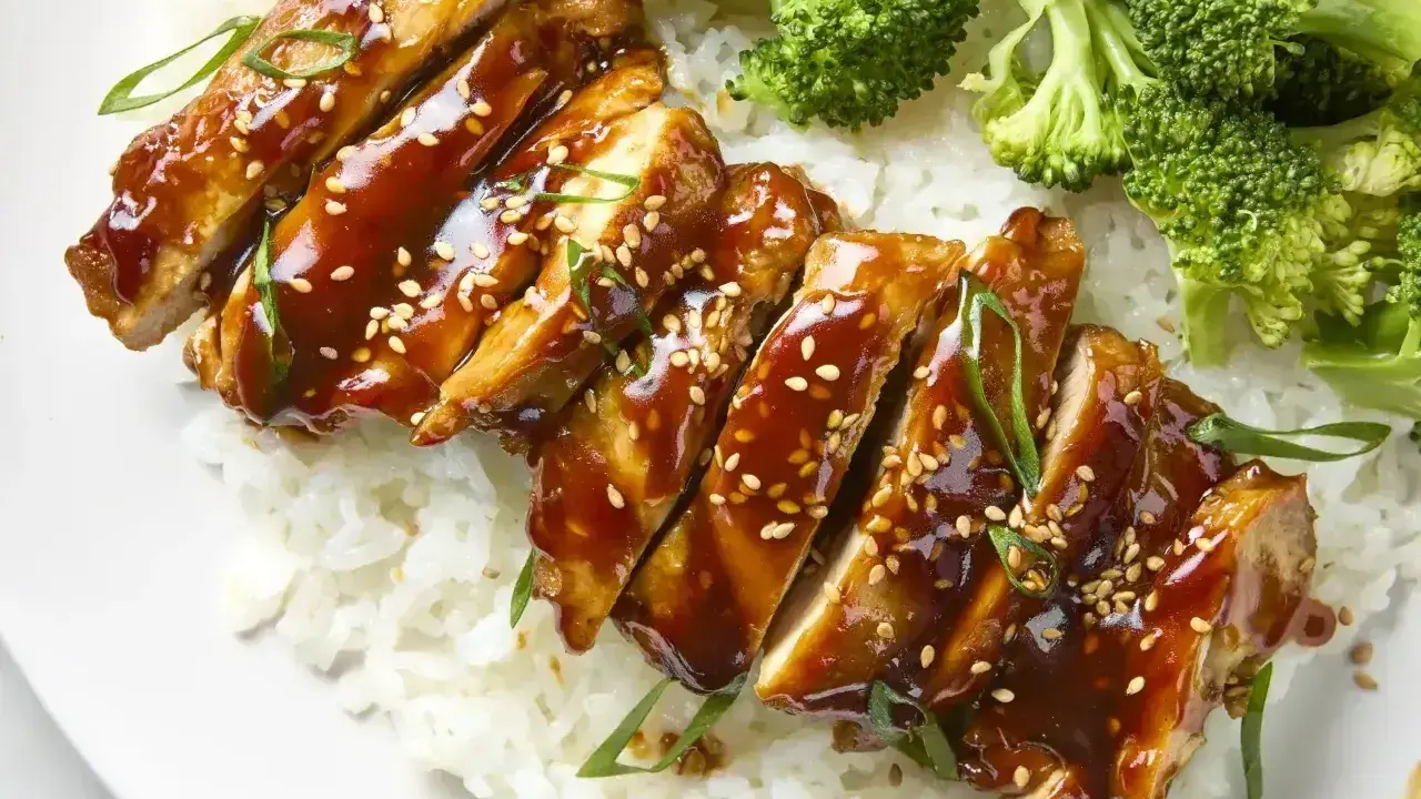 Pyszny teriyaki kurczak w sosie, podany z ryżem i brokułami. Posypany sezamem i szczypiorkiem.