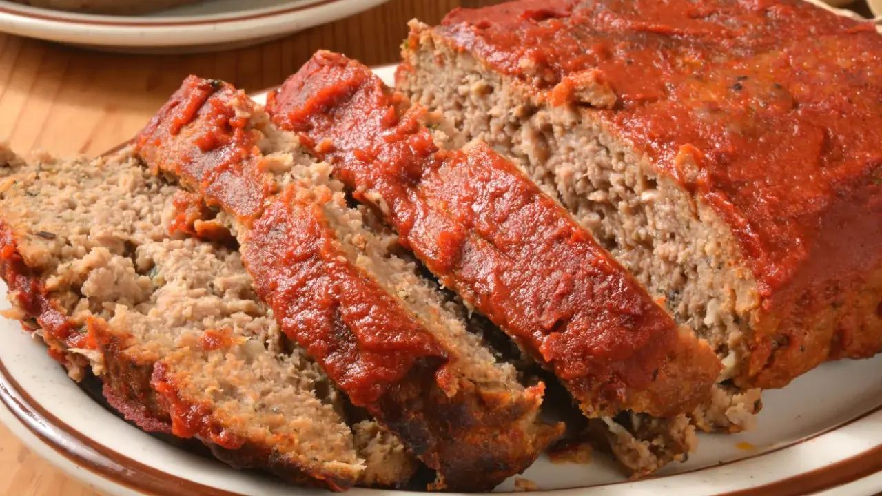 Pokrojona klasyczna pieczeń rzymska z sosem pomidorowym na talerzu.