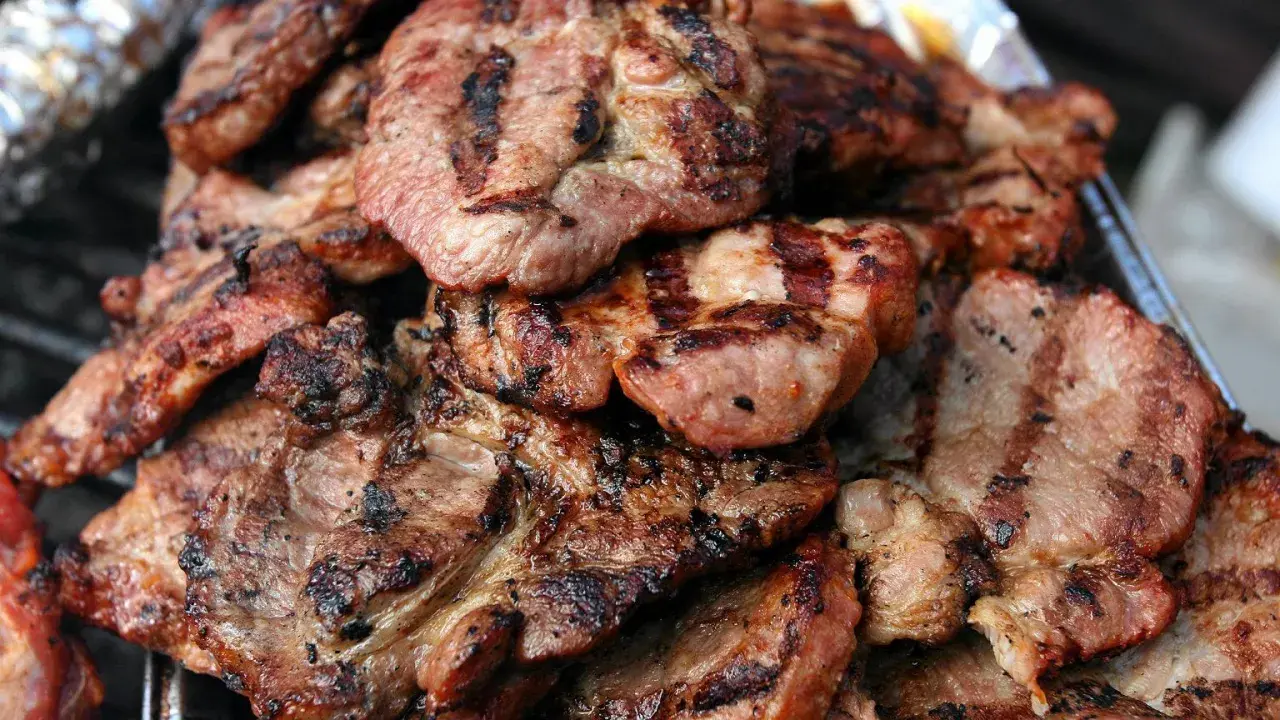 Soczysta karkówka z grilla, idealna marynata do karkówki na grilla okrasa. Grillowane plastry mięsa z charakterystycznymi paskami.