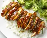 Pyszny teriyaki kurczak w sosie, podany z ryżem i brokułami. Posypany sezamem i szczypiorkiem.