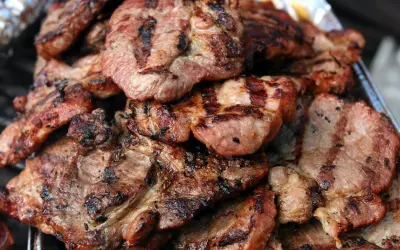 Soczysta karkówka z grilla, idealna marynata do karkówki na grilla okrasa. Grillowane plastry mięsa z charakterystycznymi paskami.