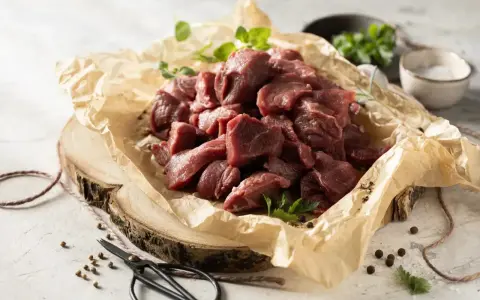 Pokrojone w kostkę mięso na gulasz z dzika, ułożone na papierze, gotowe do przyrządzenia.