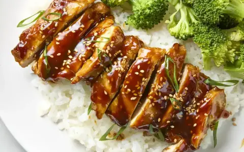 Pyszny teriyaki kurczak w sosie, podany z ryżem i brokułami. Posypany sezamem i szczypiorkiem.