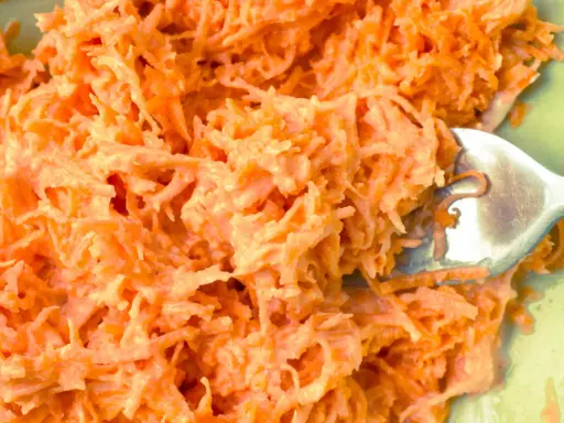 Pyszna surówka z marchewki jak z restauracji, kremowa i apetyczna. Widok z bliska na starte marchewki z sosem.