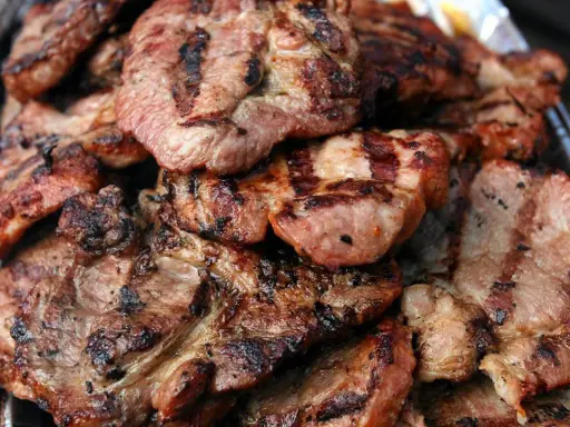 Soczysta karkówka z grilla, idealna marynata do karkówki na grilla okrasa. Grillowane plastry mięsa z charakterystycznymi paskami.
