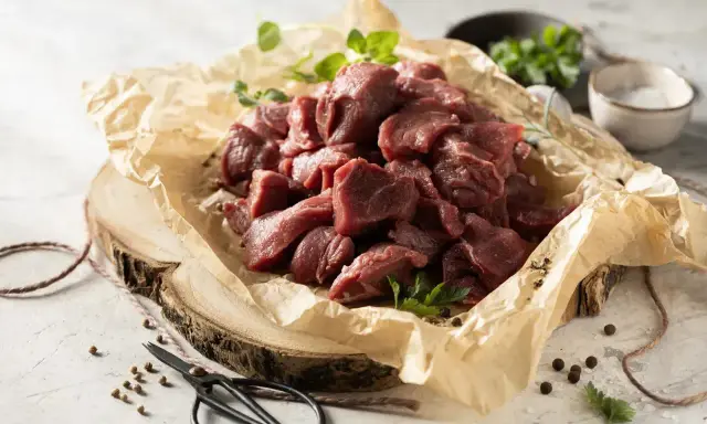 Pokrojone w kostkę mięso na gulasz z dzika, ułożone na papierze, gotowe do przyrządzenia.