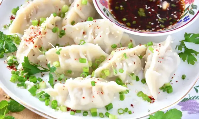 Pyszne pierogi gyoza, posypane szczypiorkiem i sezamem, podane z sosem.