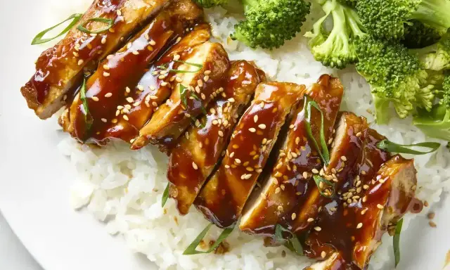 Pyszny teriyaki kurczak w sosie, podany z ryżem i brokułami. Posypany sezamem i szczypiorkiem.