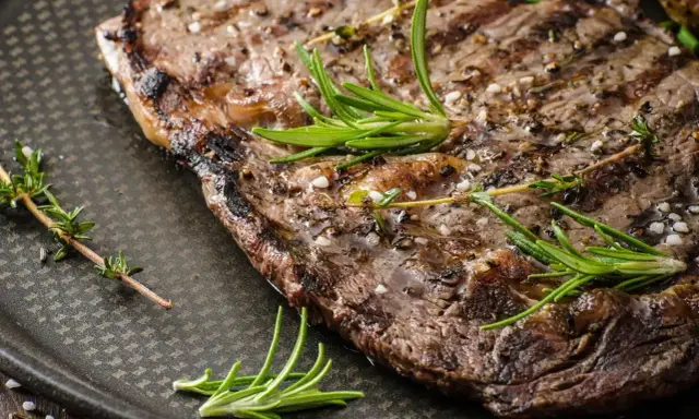 Soczysty stek z grilla, doprawiony ziołami i solą, kusi apetycznym wyglądem.
