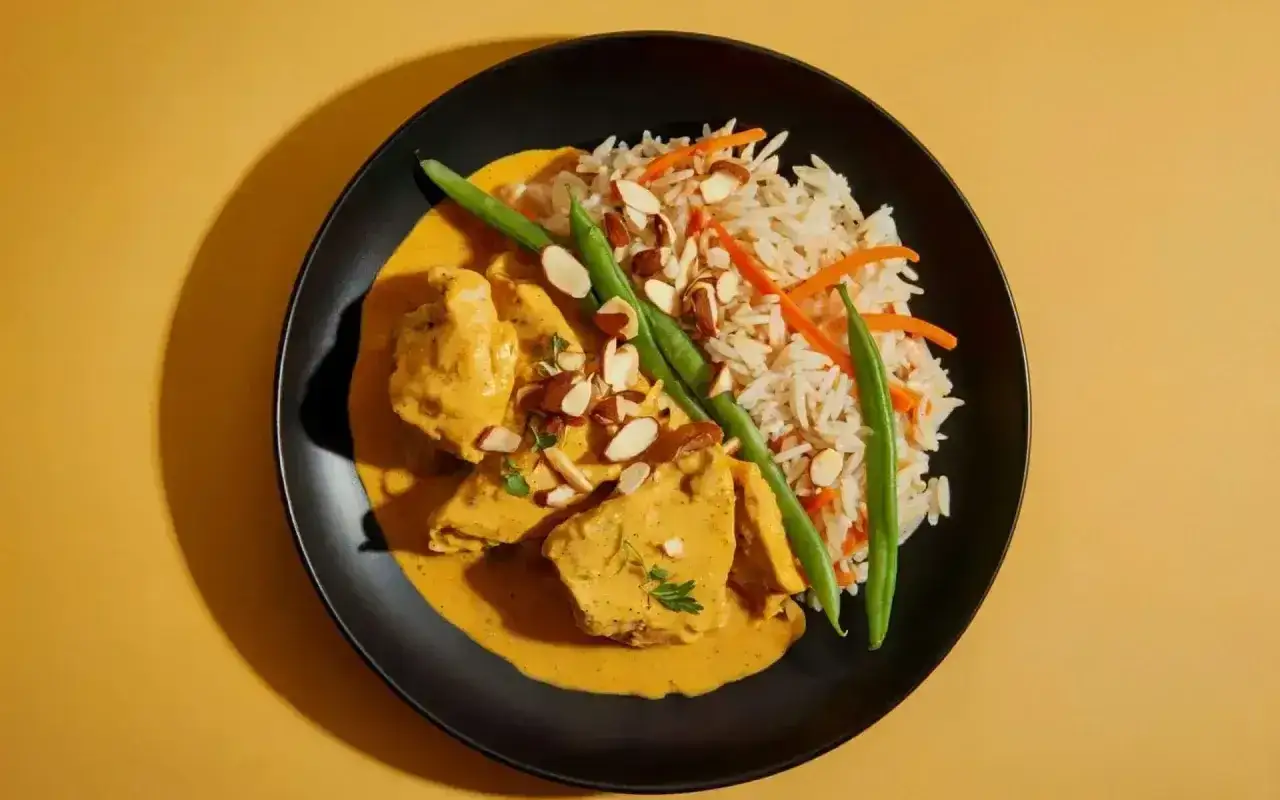 Aksamitny kurczak curry w kremowym sosie, podany z ryżem basmati, fasolką szparagową i migdałami.