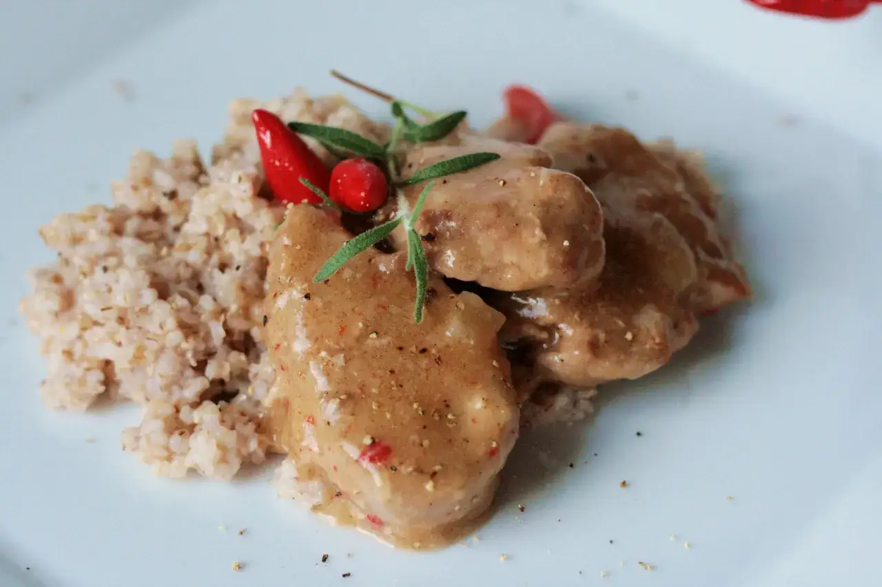 Polędwiczki wieprzowe w sosie własnym, danie Ani gotuje, podane z kaszą, ozdobione chili i rozmarynem.