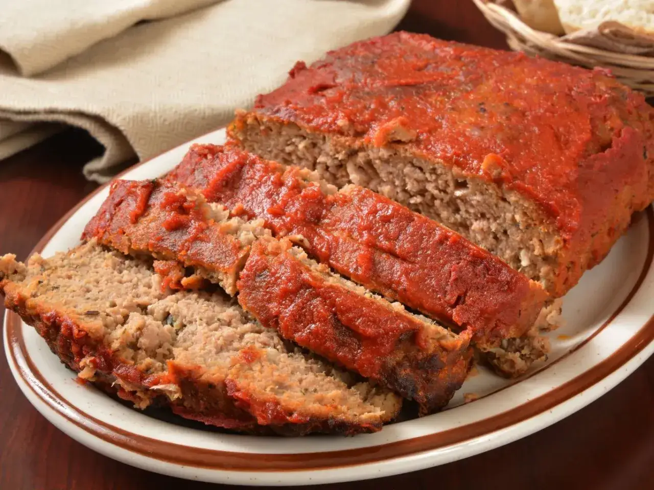 Krojona klasyczna pieczeń rzymska z sosem pomidorowym na talerzu, gotowa do podania.