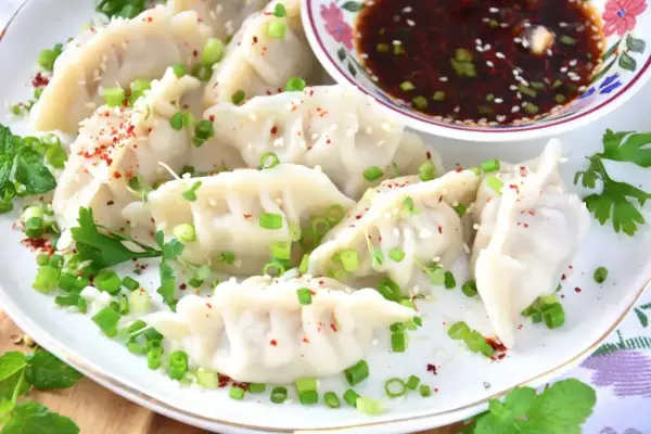 Pyszne pierogi gyoza, posypane szczypiorkiem i sezamem, podane z sosem.