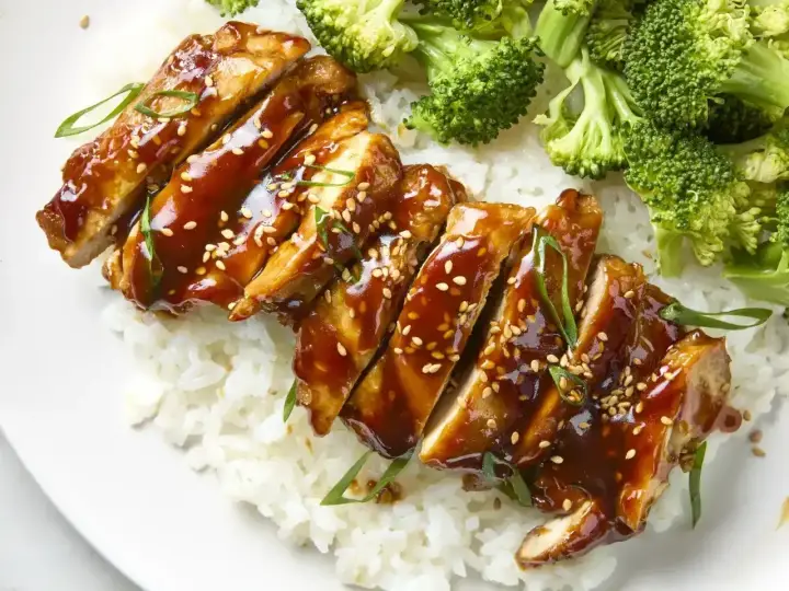 Pyszny teriyaki kurczak w sosie, podany z ryżem i brokułami. Posypany sezamem i szczypiorkiem.